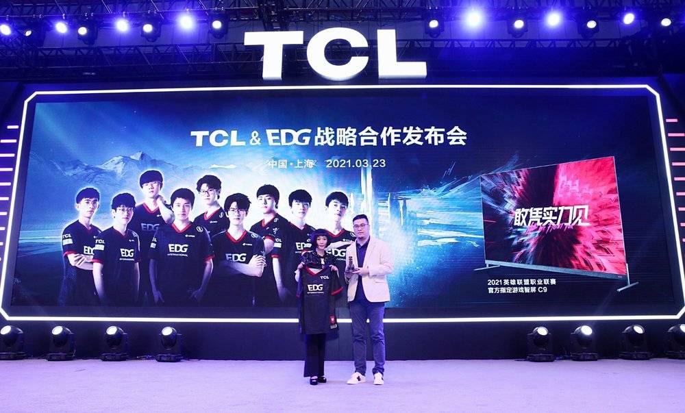 （图注：TCL科技副总裁魏雪（左）和超竞集团副总裁、EDG总经理潘逸斌（右）交换礼物）