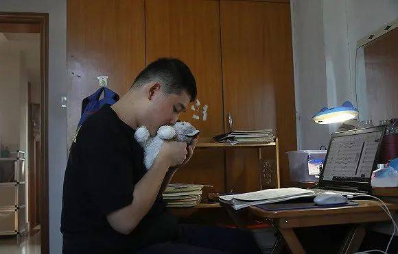 一哲是一名来自深圳的自闭症少年，他与几名伙伴创建了Jazzy Pie爵士乐队。一哲在把自己所作的曲谱输入电脑之余，闲暇之时亲吻一下玩具的“小狗”。（来源：视觉中国）
