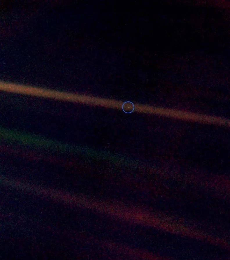 淡蓝色的小点：这是从40亿英里外的太空拍摄的地球照片，可见地球只是太阳光束上的一个小点而已（图中被人工加上的蓝圈内小点）。© wikipedia<br>