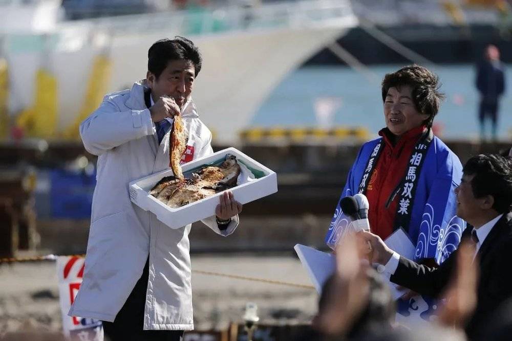 2014年12月2日，为了证明福岛食品的安全性，日本首相安倍晋三在福岛县相马市的相马原釜渔港吃了当地的烤鱼<br>