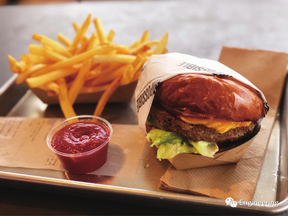 图2. 2018年，美国加利福尼亚州推出了植物汉堡Impossible Burger。这种以豆类为基础的“肉类”含有一种名为亚铁血红素的小分子，这种小分子是在装有转基因酵母的巨大容器中发酵产生的。亚铁血红素可以使植物汉堡Impossible Burger在烹饪时保持其中间人造肉肉质的粉红色，并赋予它肉的味道。注：Sarah Stierch, Wikimedia Commons (CC BY 4.0)