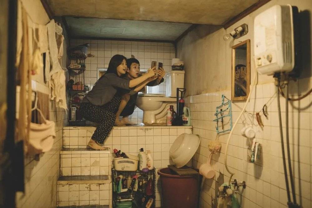 《寄生虫》中，居住在地下室的姐弟俩在寻找wifi。/《寄生虫》<br>