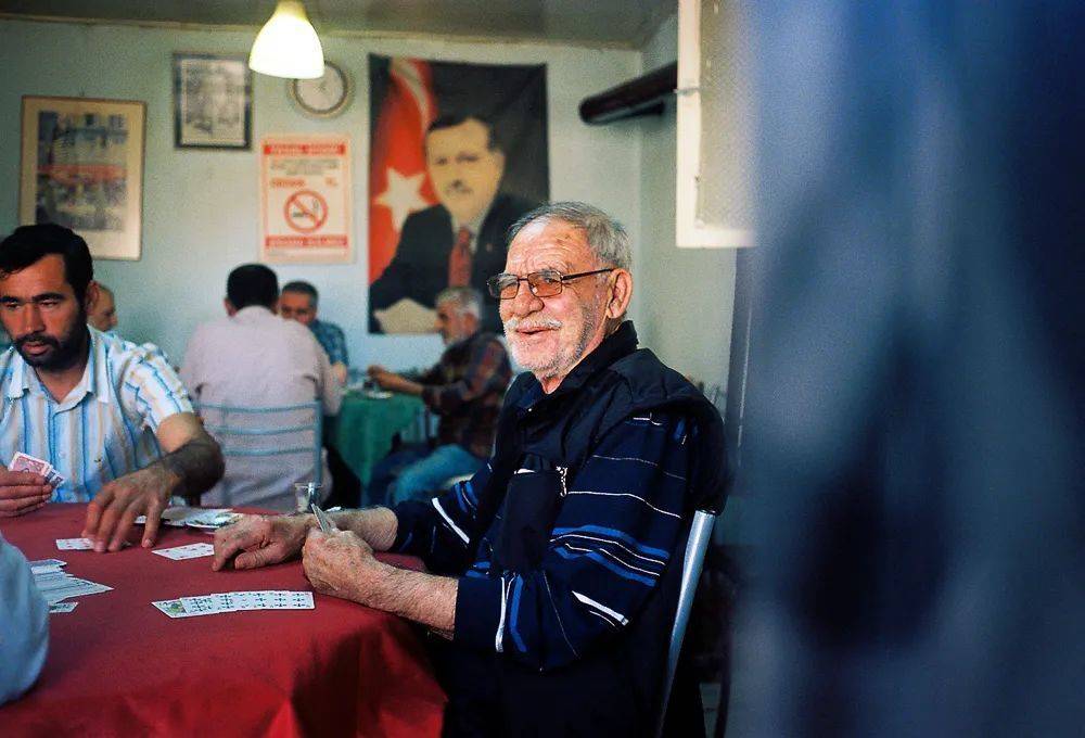 棋牌室里正在打扑克牌的老人，身后的墙壁上张贴着土耳其现任总统埃尔多安的海报。<br>
