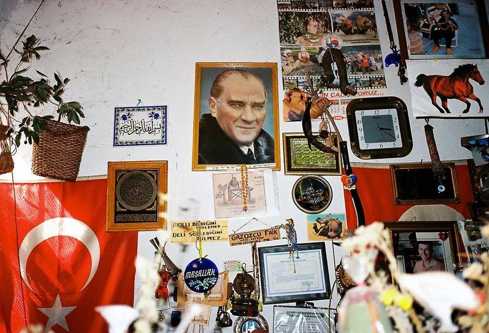 一家小型造船厂的员工办公室，墙面贴满花花绿绿的各式小玩意儿，土耳其国父穆斯塔法·凯末尔·阿塔图尔克的画像占据着最显眼的位置。<br>