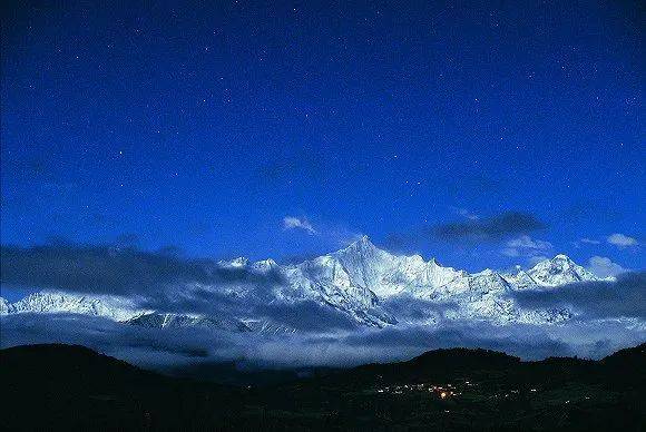 月光下的卡瓦格博。这座神山从未有人登顶过，山下有灯光的地方是飞来寺村  摄影：小林尚礼 出版社供图<br>