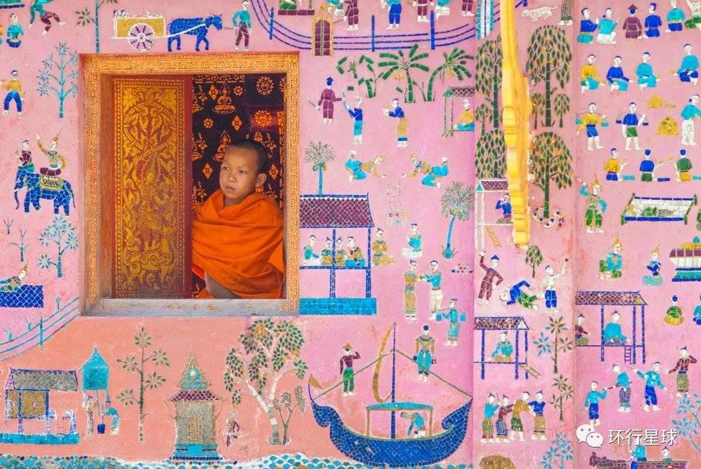 琅勃拉邦香通寺里的一位novice，该面墙上镶嵌着生命之树图案。图：Art789 / Shutterstock
