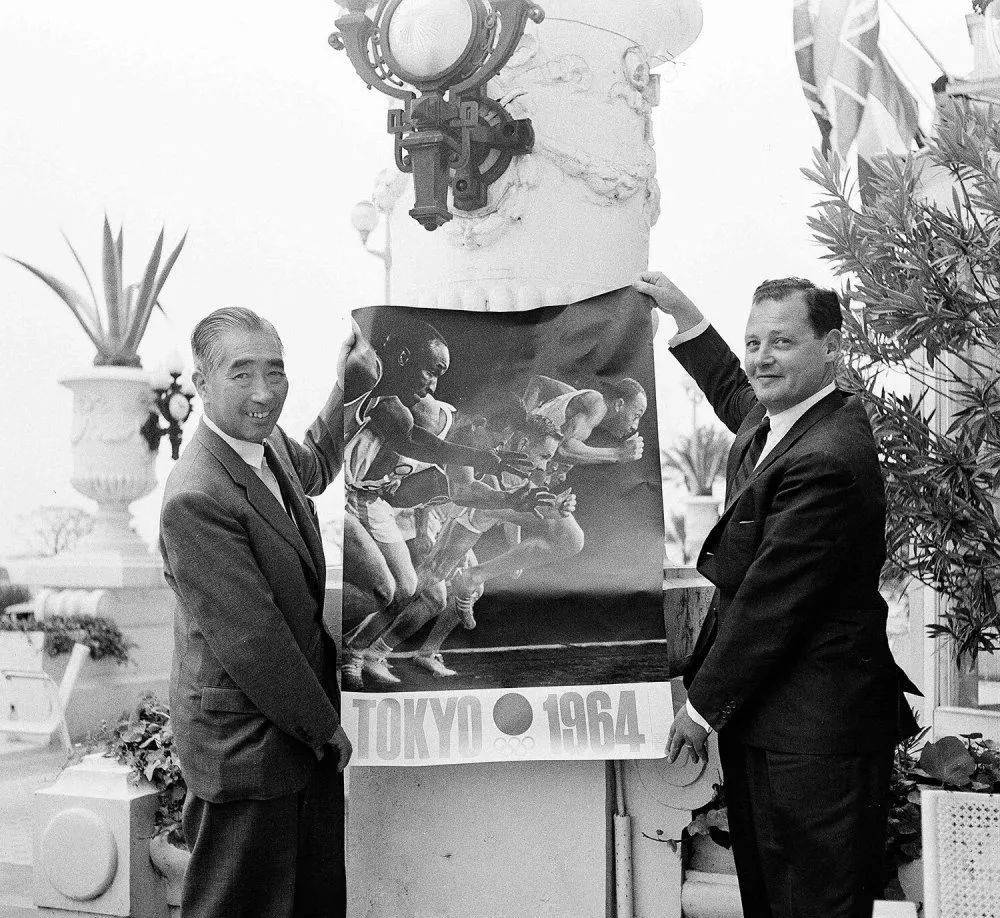 1962 年 6 月 14 日，将担任 1964 年东京奥运会主席的日本竹田恒和（左）在法国尼斯展示下一届奥运会的官方海报。<br label=图片备注 class=text-img-note>