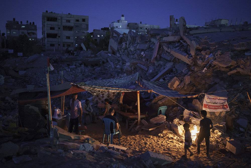 2021年6月4日，加沙地带北部贝特拉西亚，巴勒斯坦人坐在巴以冲突空袭废墟中搭建的临时帐篷里。