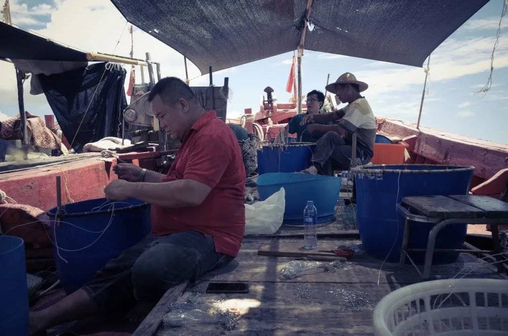 闲不下来，一有空渔民就要准备作业工具，图里的两个渔民（左、右）都在为鱼绳套鱼钩 <br>