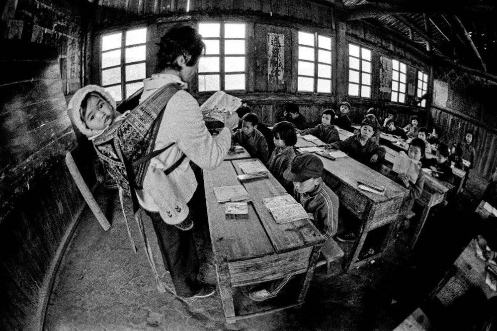 1987年 4月， 广西壮族自治区融水县安太乡寨怀村小学的戴红英老师背着不满五个月的小女儿上课。摄影/解海龙
