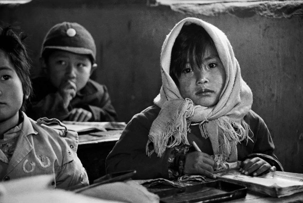 1991年9月，陕西省绥德县楼沟村小学的学生们在窑洞里上课，每人都有一块石板当写字本用。摄影/解海龙