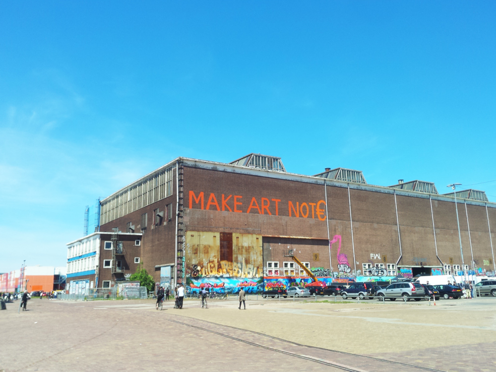 图片里的建筑是阿姆斯特丹北部靠近码头的一个老仓库，现已废弃，改为一些艺术展和乔丹鞋展会的场所。上面的标语是“做艺术，而不是赚欧元”。