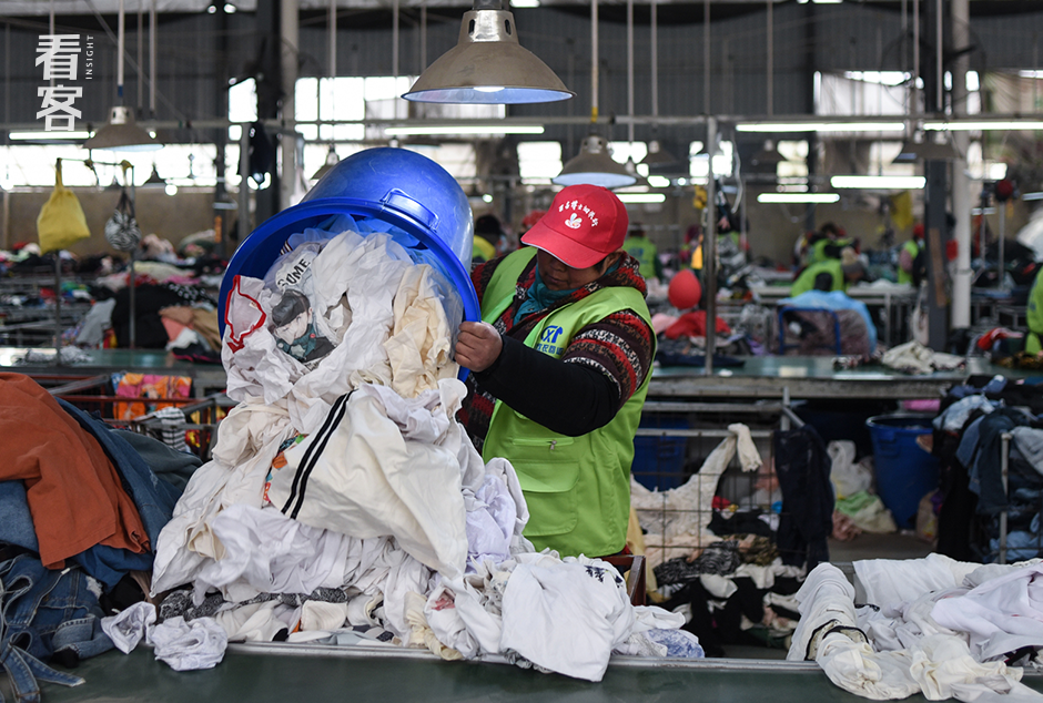 工人倾倒白料，这些旧衣将会转化成再生材料，循环利用