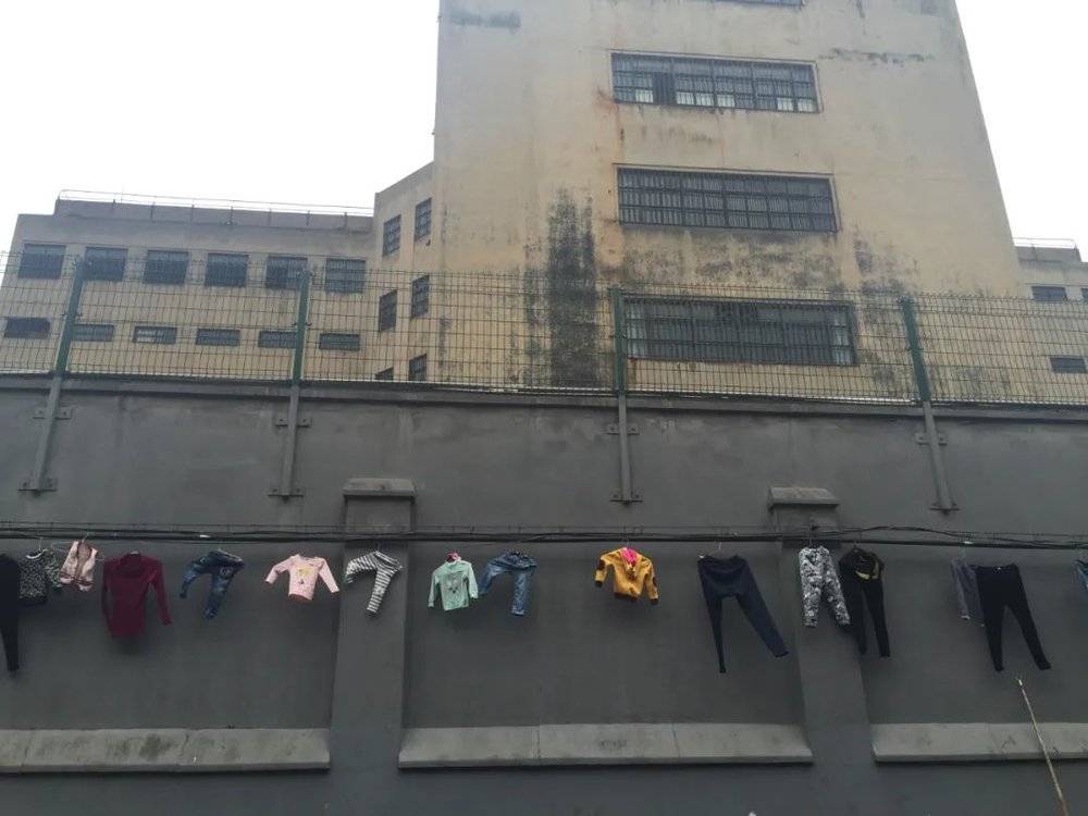 有一排小商户紧挨着提篮桥监狱，晾晒的衣物就挂在监狱围墙边  摄于2016年4月