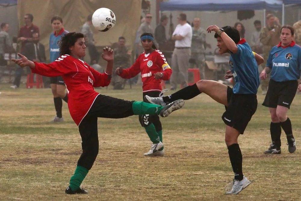2010 年，阿富汗女足队员们（红色球衣）与国际安全援助部队的队伍（蓝色球衣）踢了一场友谊赛，最终以 1-0 的成绩获胜