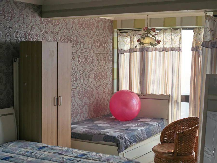 狭小空间里同时摆了三张床，健身球还摆在床上，模特已经回到自己的国家   “北京公寓”系列作品 138×103.44cm 艺术微喷 2015-2021