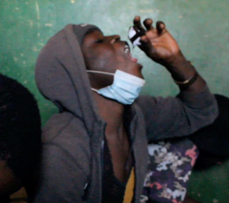 我们偷偷拍到的照片。贫民窟里的年轻人正在喝止咳药水。图片来源：自己拍的