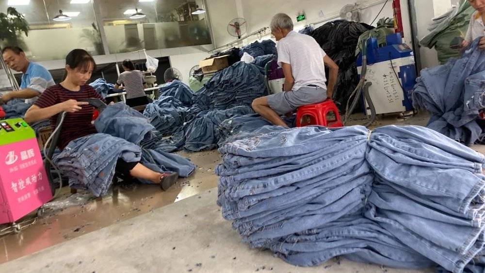 △ 工人在用机器清理牛仔裤的线头  时代周报记者黎广/摄<br>