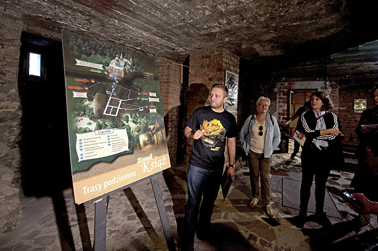 2015年9月，导游解释着瓦乌布日赫此前一座城堡下的地下通道系统，他穿的衣服上就印着火车和瓦乌布日赫字样。<br label=图片备注 class=text-img-note>