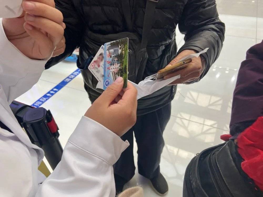 10 月 29 日，江苏一对夫妇在向北京大学人民医院工作人员展示社保卡和往日挂号单，杨宇英子摄