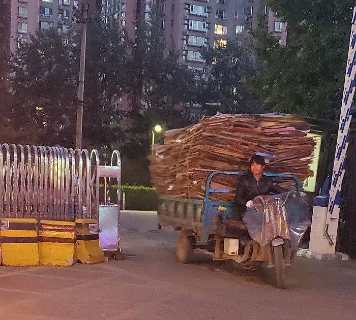 废品回收站工作人员正从北京某小区内运出当日纸箱  记者牛钰摄