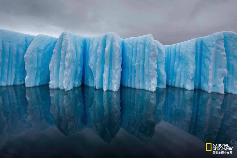 南极半岛是地球上升温最快的地区之一，融化的水在南极冰山上刻出一道道沟槽。未来20年里，这里的升温幅度预计将超过1.1℃。