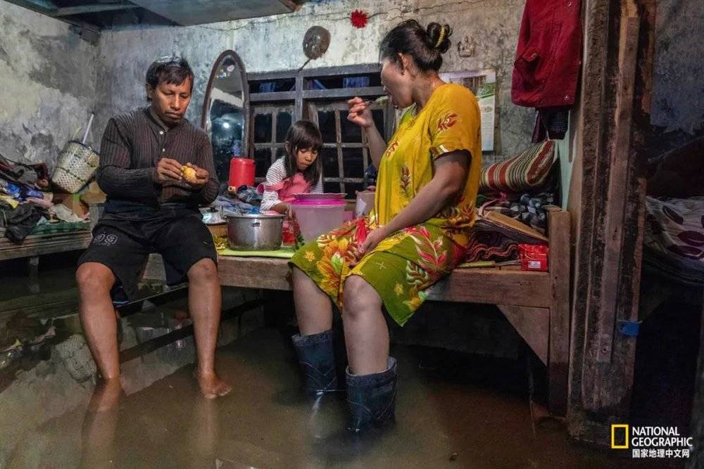 在印度尼西亚爪哇省，一家人在被洪水淹没的家里吃饭；40多年来，他们看着肥沃的农田慢慢消失于大海。