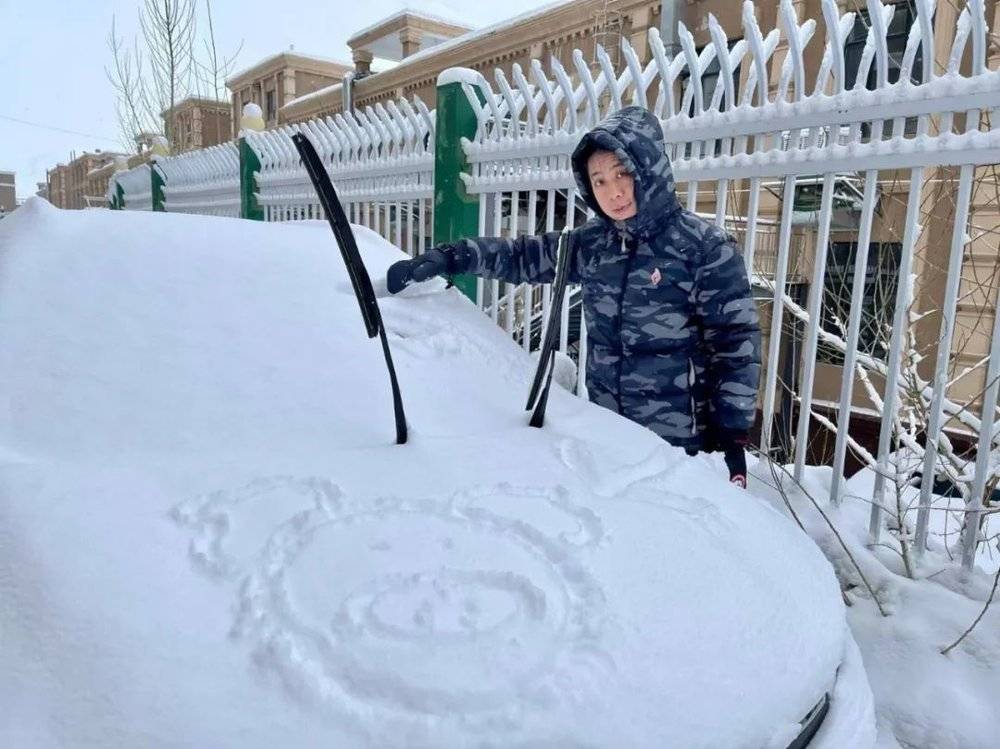 林百能在小区外为自己的车除雪。<br>