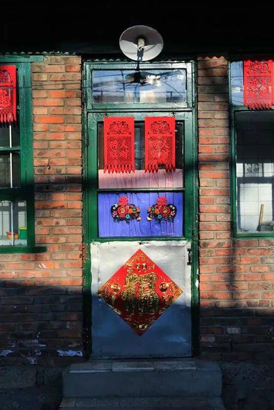 图中门窗上的红色剪纸叫做“吊钱儿”，是北方常见的春节装饰用品。大城市中，唯有天津自始至终保持着这种民俗。摄影/张建