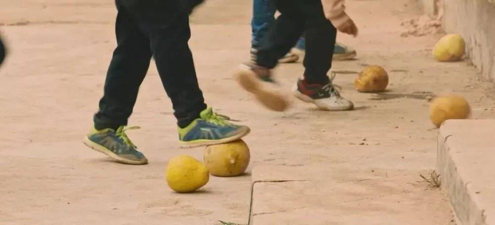 △以前的梅州乡村里，少年用柚子踢球。/视频截图<br>