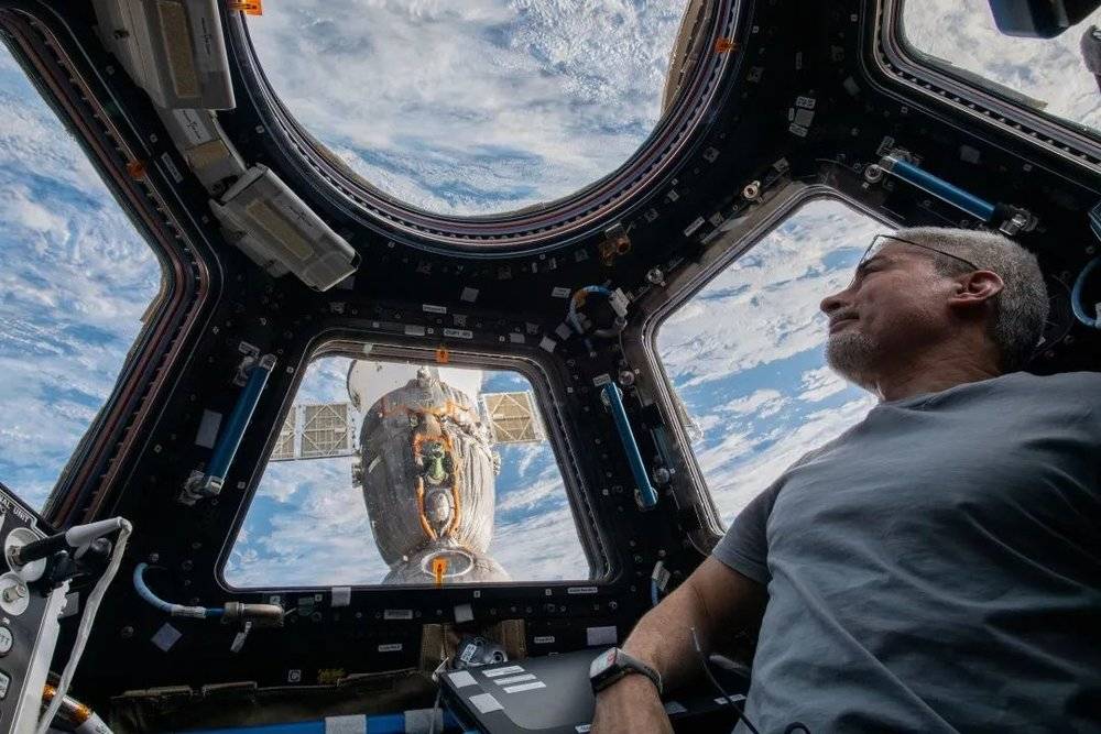 美国宇航员Mark Vande Hei在国际空间站穹顶舱俯瞰地球，窗外就是俄罗斯的联盟号MS-19载人飞船。他将乘坐这艘俄罗斯飞船于今年3月返回地球。｜NASA<br label=图片备注 class=text-img-note>
