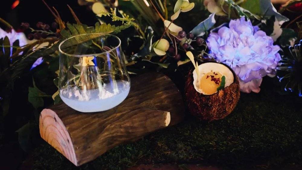 荨麻酒及蜜瓜酒调制的冰蓝色鸡尾酒和盛在椰子壳中的热带风味甜点。