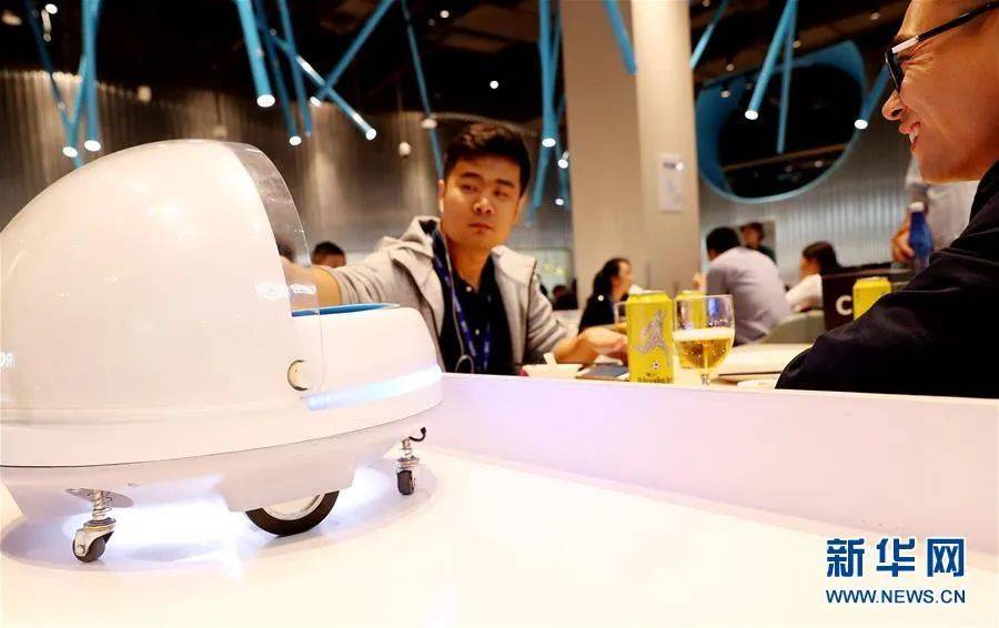 顾客从送餐机器人的装载平台上取下菜品。新华社（记者 方喆 摄）<br>