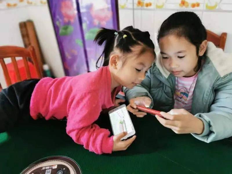 广西金秀县，两名儿童正在玩手机。何鲜桂摄/光明图片