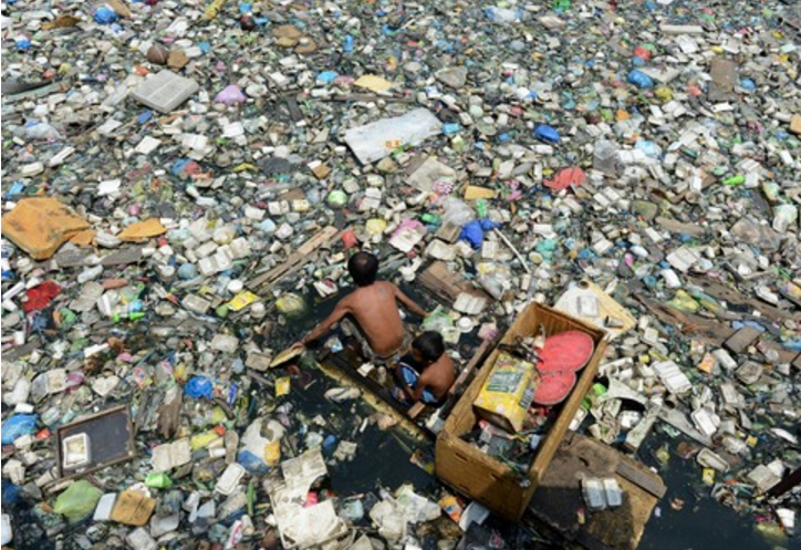 在菲律宾首都马尼拉，一对父子坐着小船划过漂满垃圾的河道<br label=图片备注 class=text-img-note>