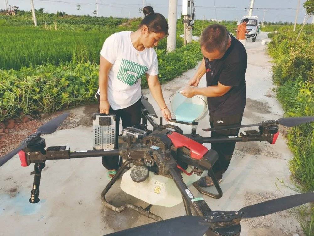 ▲李新玲和丈夫李亚在田间给无人机灌药。王腾飞 摄<br>