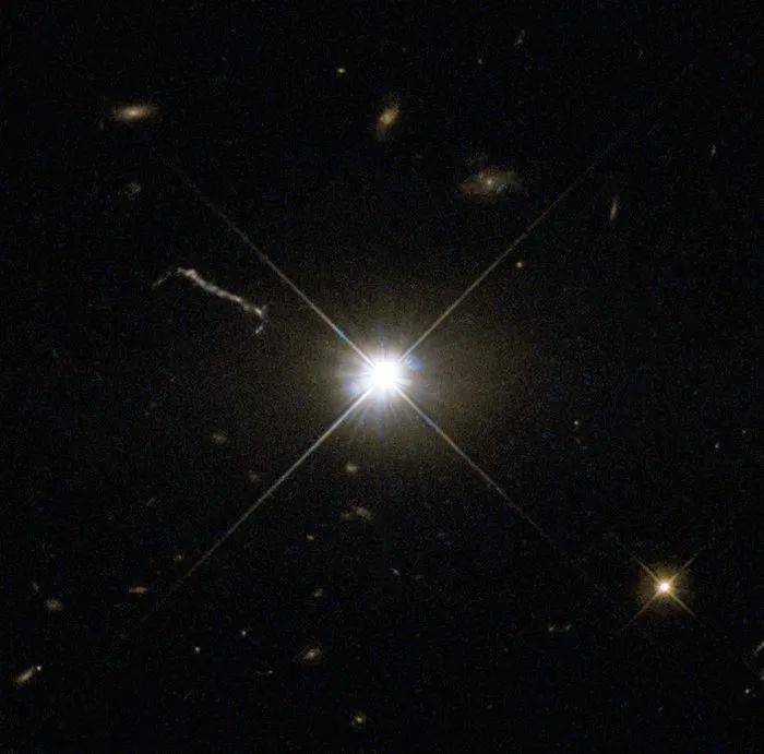 哈勃空间望远镜（“哈勃”）的WFPC2拍摄的3C 273（中心亮点）的可见光图像。中心亮点左上方的一条柱状条纹是它发出的喷流，长度达到了20万光年左右。图片来源：[9]<br label=图片备注 class=text-img-note>