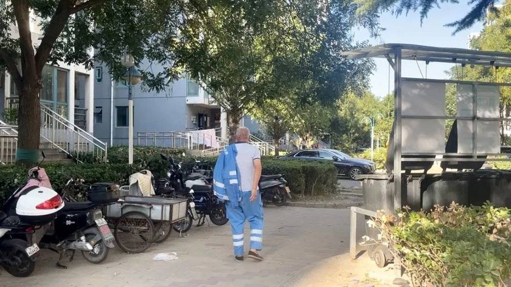 9月20日下午，北京某小区内，六十多岁的河南环卫工结束一天的工作，往住处走去。他住在单位提供的铁皮房里，三四人同住一间。摄影/郑可书