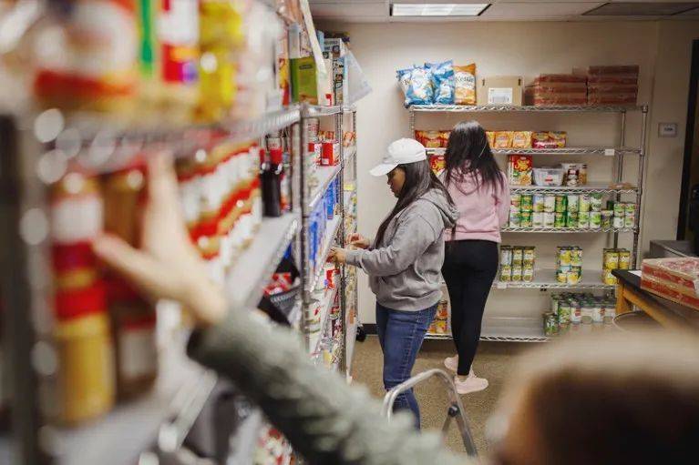 在佐治亚州肯尼索州立大学的CARE食品库（一个食物银行），学生志愿者和工人正在往货架上装货并清点库存。来源：Melissa Golden/Redux/eyevine<br label=图片备注 class=text-img-note>