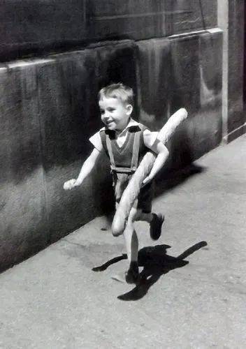 著名黑白照片《小巴黎人》，小男孩紧抱着法棍在大街上幸福飞奔