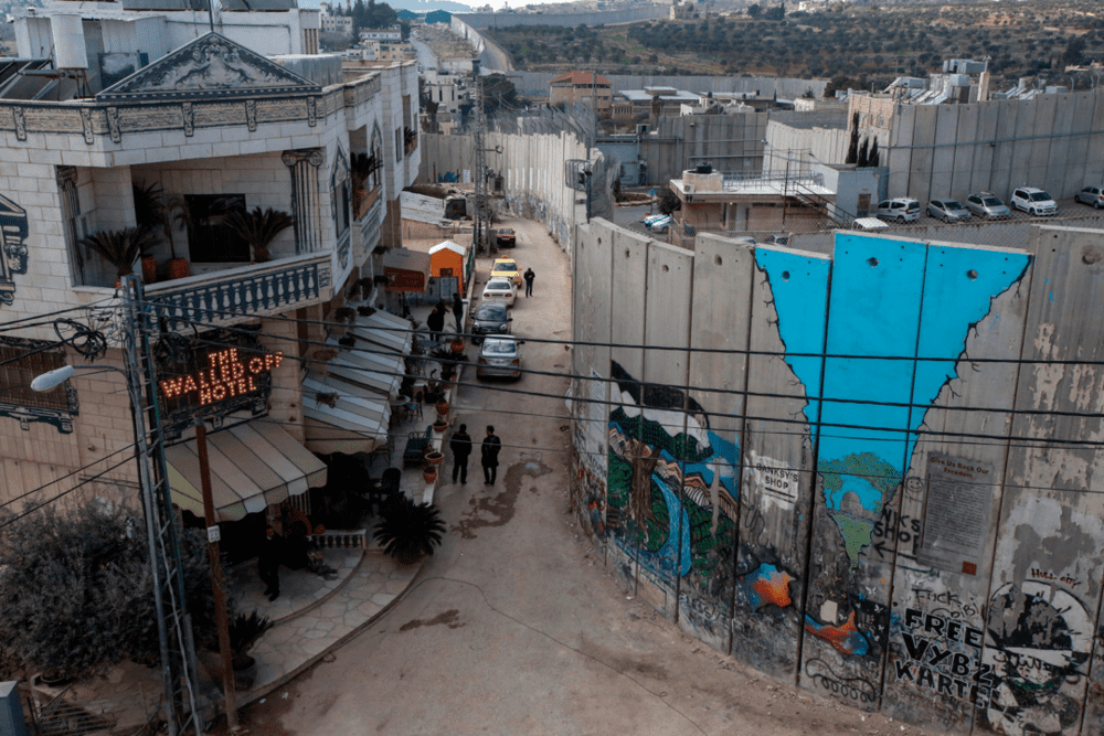 位于伯利恒段的巴勒斯坦隔离墙，旁边是涂鸦艺术家Banksy投资的围墙酒店 <br label=图片备注 class=text-img-note>