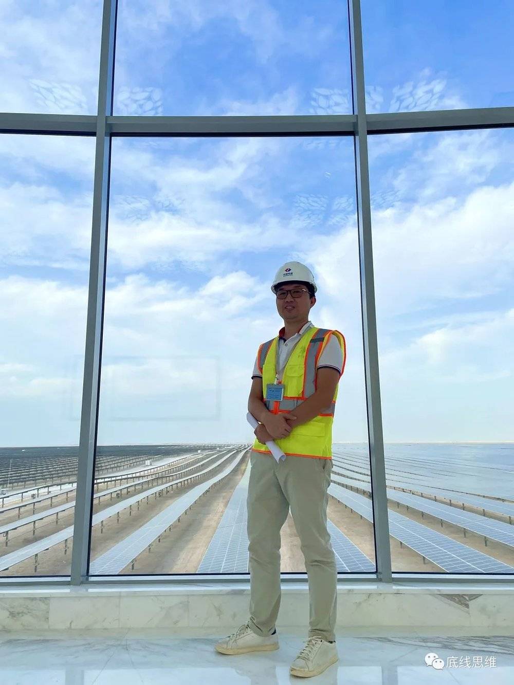图为受访者，背景为中国电建贵州工程公司所承建的阿尔卡萨800兆瓦光伏发电项目（受访者供图）<br>