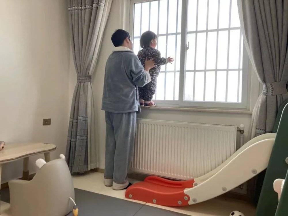 爸爸抱着孩子看窗外。/受访者供图<br>