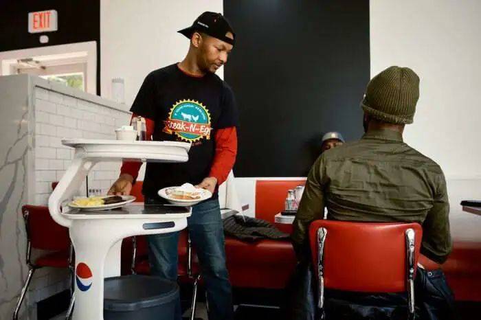 华盛顿特区的Steak N Egg Diner餐厅，一台名为Servi的机器人协助店员为顾客上菜。图源：巴伦周刊