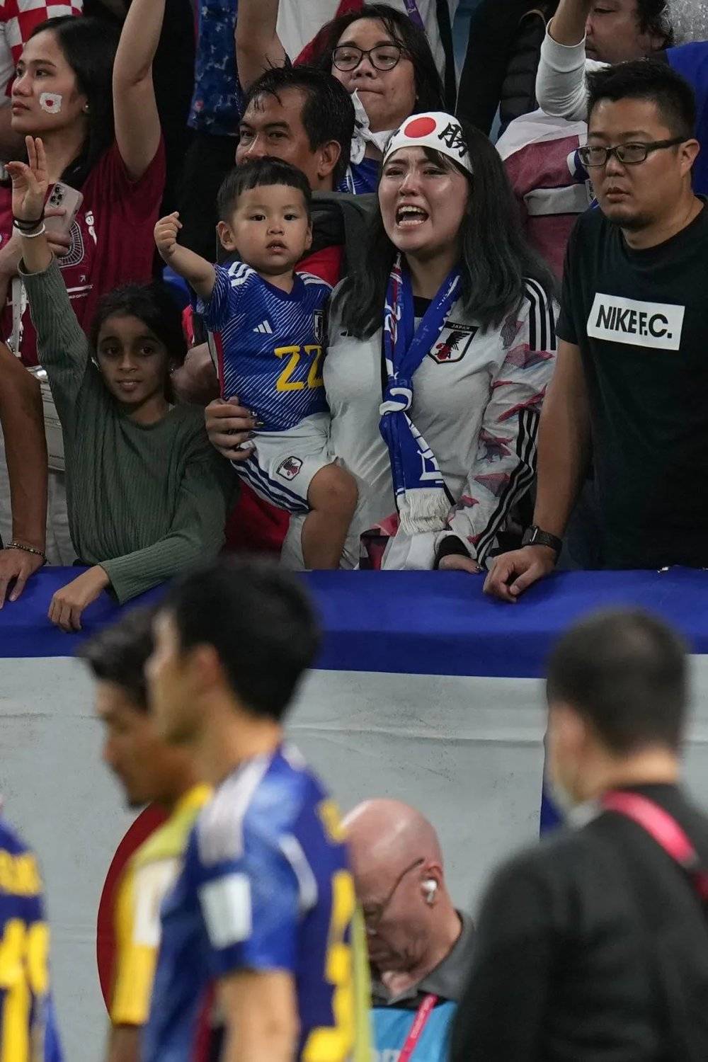 一名抱着孩子的日本球迷在日本队失利后仍为其加油助威