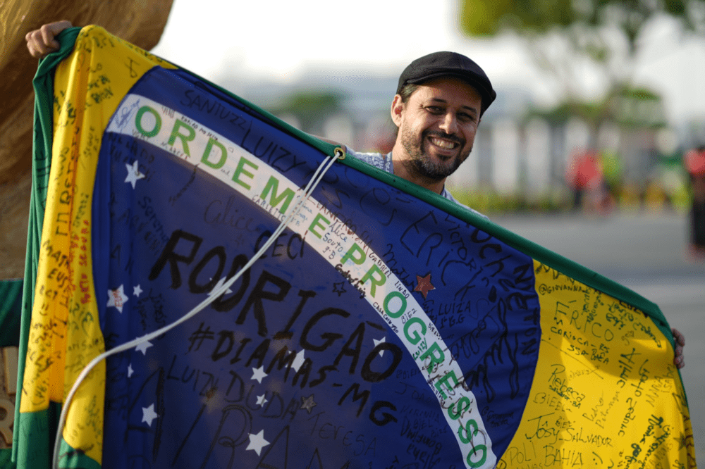 来自巴西的Anderson，在哈里发国际体育场外，展示签满其友人名字的巴西国旗<br>