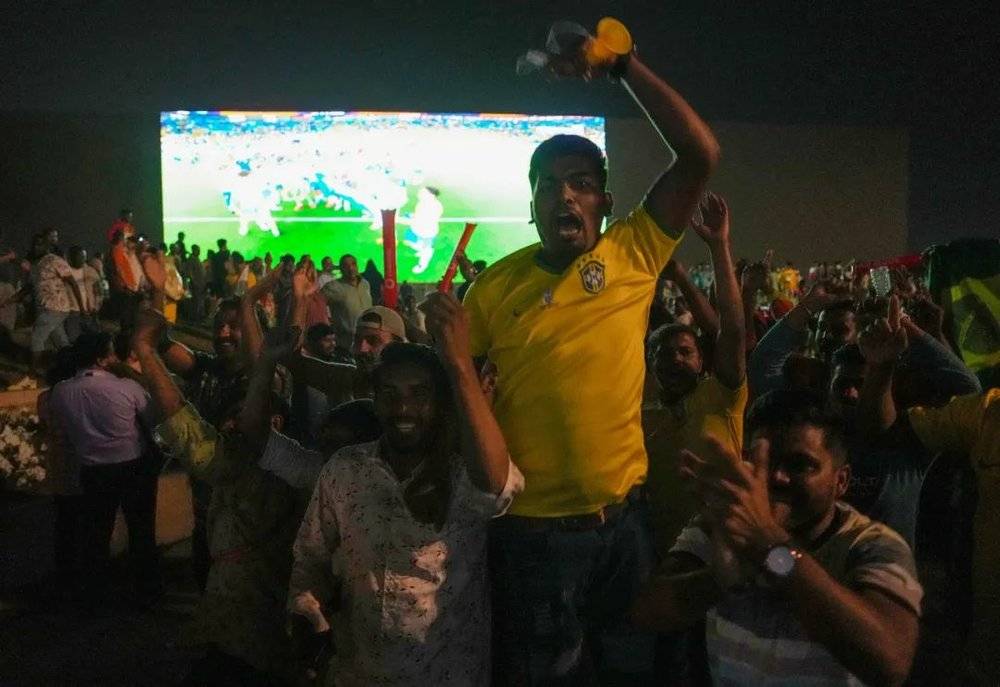 当地劳工在多哈海滨大道旁的巨屏观看巴西4-1胜韩国的比赛后狂欢庆祝<br>