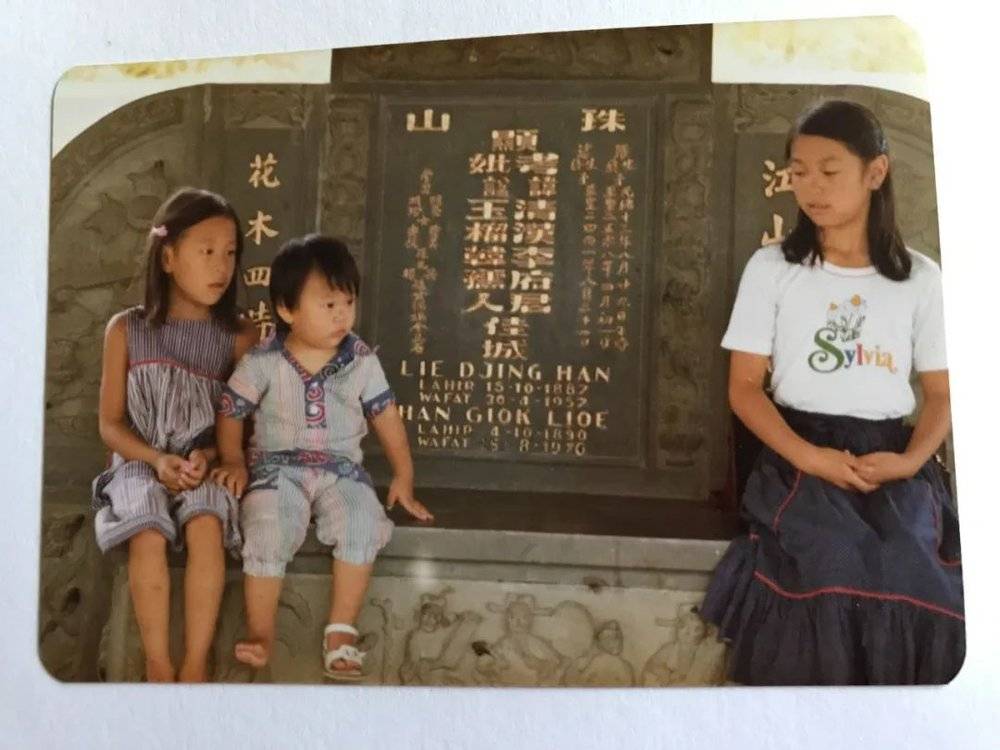 ■ 小时候的李伟汉和姐姐们在曾祖父的墓碑前
