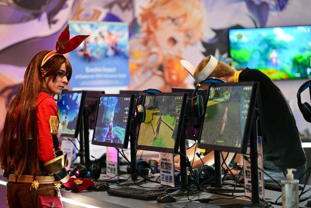 图源：视觉中国 | 2022 年 8 月 24 日，德国科隆国际游戏展，一名女玩家被《原神》吸引
