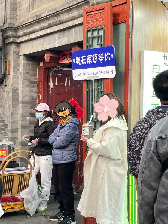 游客买完竹筒奶茶在路牌下打卡 摄影/李莹